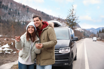 Happy couple near car on road. Winter vacation