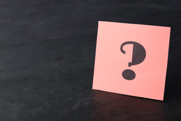 Note with question mark on black stone table. Space for text