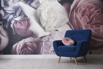 Comfortable armchair near wall with floral wallpaper, space for text. Stylish living room interior