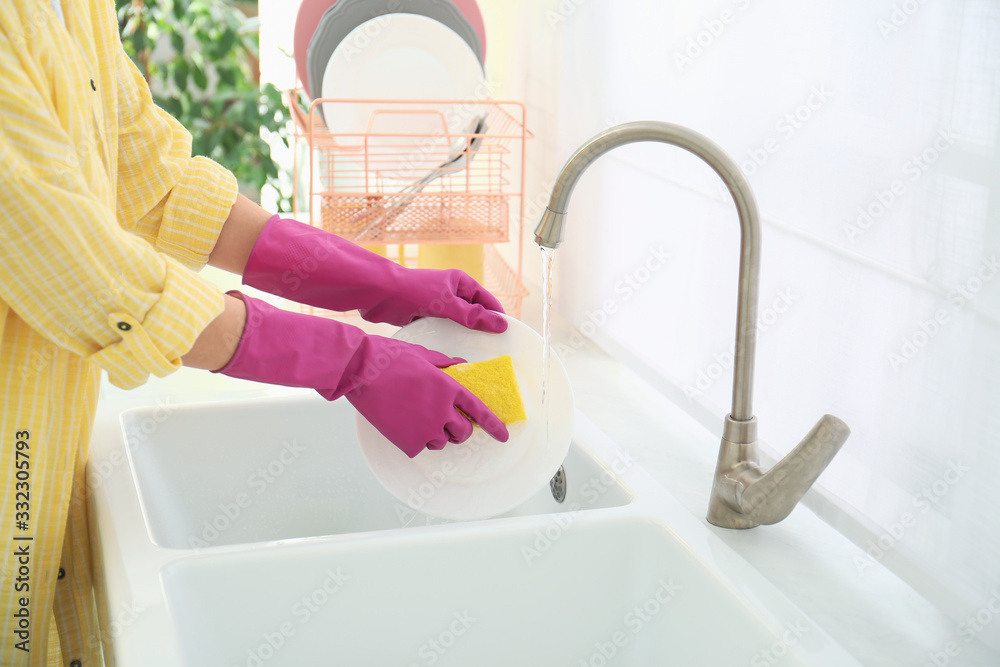 Wall mural Woman washing ceramic plate in kitchen, closeup