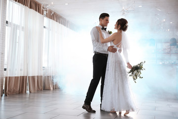 Happy newlywed couple dancing together in festive hall