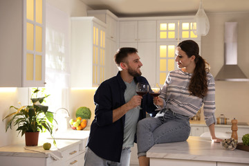 Lovely young couple drinking wine while cooking together in kitchen