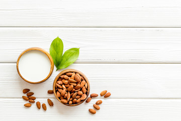 Almond milk near nuts on white wooden background top-down copy space