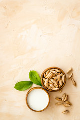 Alternative milk made from almond. Drink near unpeeled on beige table top-down copy space