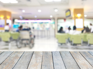 Wooden table top over blur background of people waiting to receive the medicine at the counter in hospital