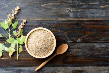 Organic raw brown quinoa seed in a bowl and quinoa plant on wooden background, healthy food