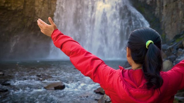 Asian woman enjoying the beautiful Rainbow Falls in the Ansel Adams Wilderness near Mammoth Lakes California USA