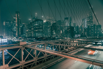 Obraz na płótnie Canvas Puente de Brooklyn en Nueva York a la noche con Manhattan al fondo y coches en movimiento 