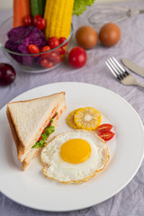 American breakfast on a white background with fried egg, salad, pumpkin, cucumber, carrot, corn, cauliflower, tomato and sandwich