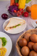 American breakfast on a white background with egg, salad, pumpkin, cucumber, carrot, corn, cauliflower, tomato and sandwich