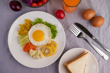 American breakfast on a white background with fried egg, salad, pumpkin, cucumber, carrot, corn, cauliflower, tomato, toast and orange juice.