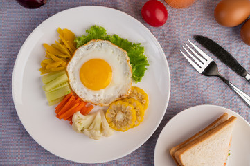 American breakfast on a white background with fried egg, salad, pumpkin, cucumber, carrot, corn, cauliflower, tomato and sandwich