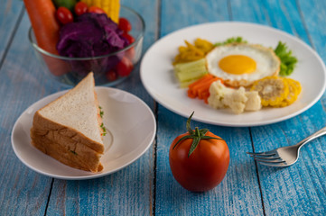 American breakfast on a white background with fried egg, salad, pumpkin, cucumber, carrot, corn, cauliflower, tomato and sandwich
