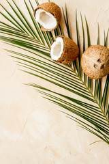 Obraz na płótnie Canvas Coconuts and leaves - tropical still life on beige background top-down copy space