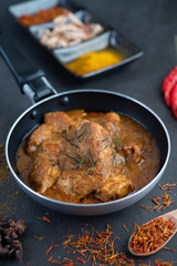 Massaman curry in a frying pan with spices on the cement floor