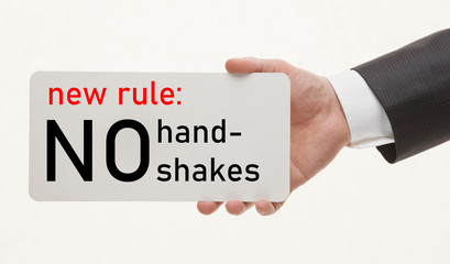 Unrecognizable man's hand demonstrates a reminder to avoid handshakes