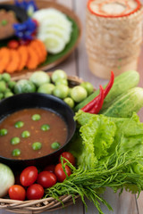 Chili paste paste in a bowl with eggplant, carrots, chili, cucumbers in a basket