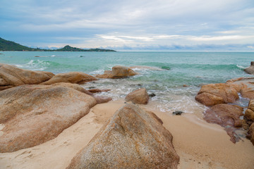 Sea and rock stones on the beach with sand and blue sky