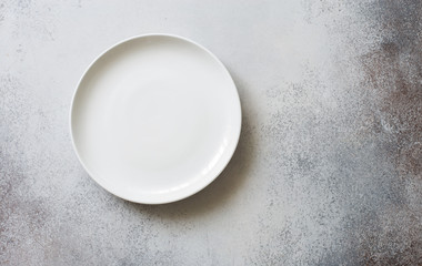White empty ceramic plate on a gray stone background