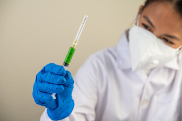 Scientists wearing masks and gloves Holding a syringe with a vaccine to prevent covid-19