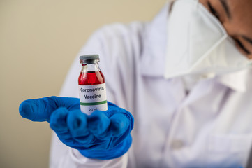 Scientists wearing masks and gloves, carrying vials with vaccines to protect Covid-19