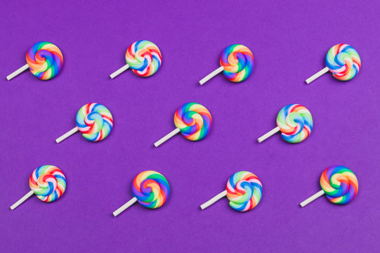 Lollipops are arranged symmetrically on a colored background. colorful candies