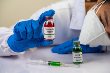 Scientists wearing masks and gloves, carrying vials with vaccines to protect Covid-19