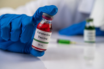 Scientists wearing masks and gloves, carrying vials with vaccines to protect Covid-19