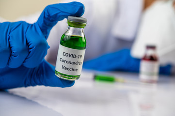 Scientists wearing masks and gloves, carrying vials with vaccines to protect Covid-19