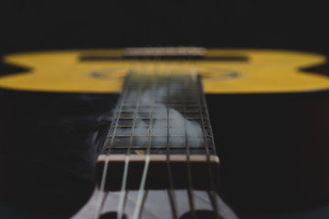 Acoustic guitar in smoke close up. musical instrument. strings on the guitar neck