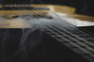 Acoustic guitar in smoke close up. musical instrument. strings on the guitar neck