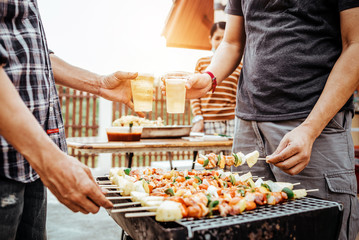 Happy man with friends making barbecue and drinking beer asian style.