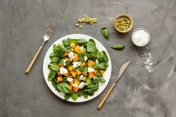 Healthy food concept. Salad with pumpkin and basil on grey background top-down