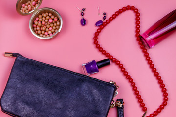 Clutch bag, red necklace, earrings, nail polish, rouge balls and bottle of perfume on pink background. Beauty and fashion concept. Flat lay, top view