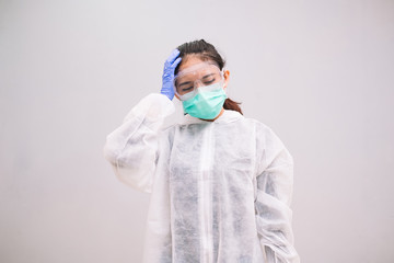 Tired Young Nurse wearing disposable coverall with mask and safety googles thinking tired and...