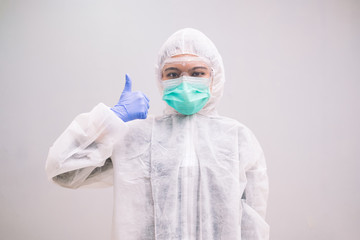 Fototapeta na wymiar Cheerful Nurse wearing disposable coverall with mask and safety google shows thumb up.Pandemic 2019 Coronavirus 2019-nCoV.