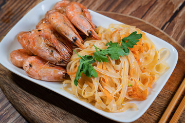 Udon noodles and fried cocktail prawns on a plate.
