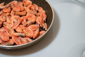 small cocktail shrimps are fried in a pan. 