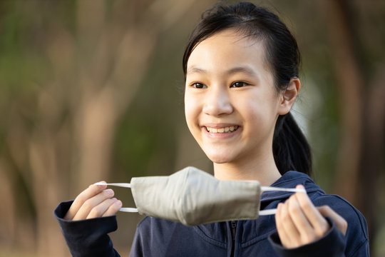 Asian Child Girl Show A Mask Made Of Fabric Woman Is Campaigning To Wear A Mask Before Leaving The House To Prevent Flu Pandemic; Contagious Or Spread Of The Coronavirus Outbreak; Epidemic Of Covid-19