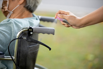 Woman is spraying alcohol,disinfectant spray on wheelchair handlebar hand,prevent...
