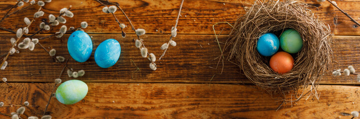 Still life of easter eggs in a bird's nest on a wooden background. Rustic. Easter celebration concept. Copy space. Flat lay. Banner.