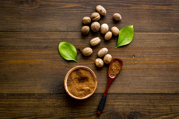 Nutmeg - ground indian condiment in spoon - on wooden background top-down