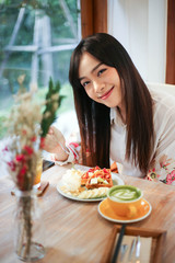 Beautiful asian woman eating delicious  waffles in coffee shop cafe.