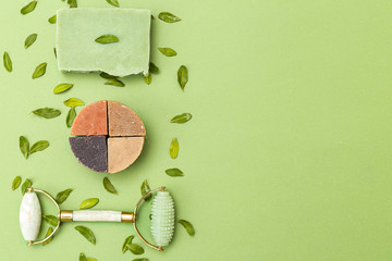 Natural soap and face roller of green color with eucalyptus leaves on a green background. Copy space.