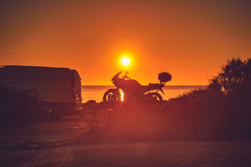 Camper van with motorcycle at sunset