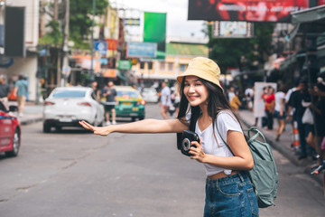 Young asian woman hold instant film camera and call taxi in Bangkok, Thailand.
