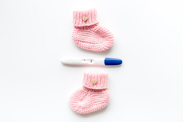 Positive pregnancy test. Baby girl concept with pink booties on white background top-down copy space