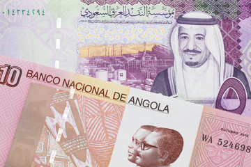 A colorful ten kwanza bill from Angola with a colorful, Saudi Arabian riyal bank note close up in macro