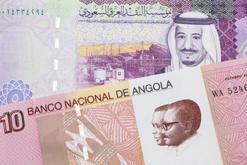 A colorful ten kwanza bill from Angola with a colorful, Saudi Arabian riyal bank note close up in macro