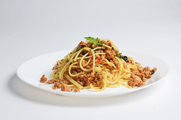 Spaghetti and fried basil chicken on white background.